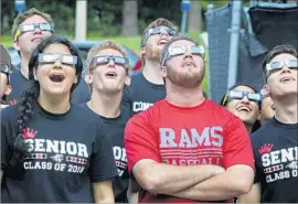  ?? Joe Burbank Orlando Sentinel ?? STUDENTS at Lake Mary High School in Florida give their solar eclipse glasses a trial run on Friday. “Seeing an eclipse is profound, eerie and intense,” one veteran eclipse chaser said. “This is not just a science event; it is a human event.”