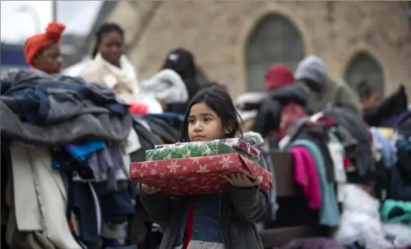  ?? Jerry Holt/Star Tribune via The Associated Press ?? Briella Jones, 5, who lived in the Francis Drake Hotel apartments with her family, holds donated Christmas presents on Wednesday in Minneapoli­s. Hundreds of people were left in the cold early Christmas morning after a four-alarm blaze at the complex.