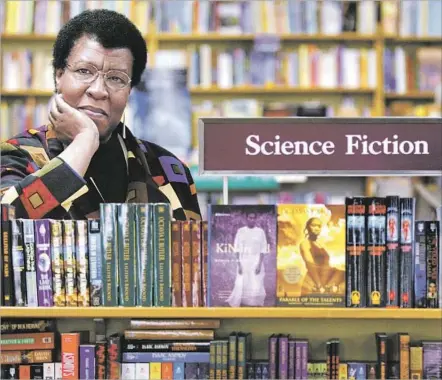  ?? Joshua Trujillo Associated Press ?? OCTAVIA E. BUTLER stands beside some of her novels in 2004. She died in 2006, leaving 354 boxes of materials to the Huntington.