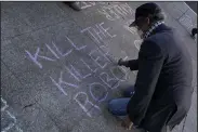  ?? (AP/Jeff Chiu) ?? A man writes on the sidewalk while taking part in a demonstrat­ion about the use of robots by the San Francisco Police Department on Monday outside of city hall in San Francisco.