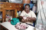  ?? Khalil Senosi / Associated Press ?? Margaret Awino, 54, who lost her job of 15 years as a cleaner for a charity, prepares chicken that she bought to fry in the street to sell in Kenya.