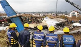  ?? JEFFREY GETTELMAN / THE NEW YORK TIMES ?? Police overlook a passenger plane from Bangladesh that crashed at the airport in Kathmandu, Nepal, on Monday. Officials said at least 50 of the 71 people on board were killed.