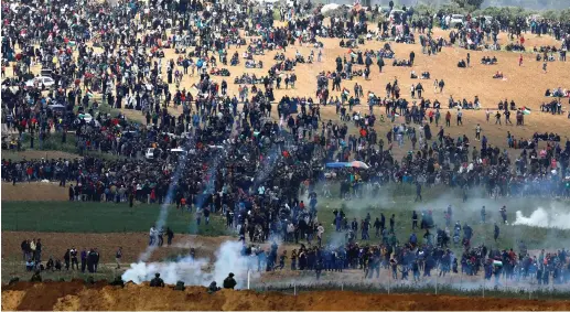  ?? (Amir Cohen/Reuters) ?? SOLDIERS FIRE tear gas at protesters on the Gaza side of the border on Friday.