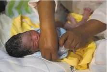  ?? Juan Karita / Associated Press ?? Newborn Abraham Dilan is dressed by midwife Ana Choque after delivering him at his parents’ home in El Alto, Bolivia.