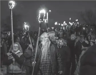  ?? MATT GADE / RAPID CITY JOURNAL VIA AP ?? People carry torches en route to the beetle effigy before setting it on fire during the 11th annual Burning Beetle event on Saturday at Pageant Park in Custer, South Dakota.