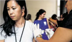  ?? Houston Chronicle file ?? Baylor College of Medicine research director Dan Na Luo, left, receives a flu shot from Certified Medical Assistant Rebecca Slappey.