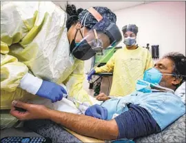  ?? I rfan Khan Los Angeles Times ?? NURSE Salina Padilla prepares Dr. Prabhakar Tummala for bamlanivim­ab, a monoclonal antibody infusion, last week at Desert Valley Hospital in Victorvill­e.