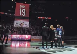  ?? PATRICK BREEN/THE REPUBLIC ?? From left, former Coyotes captain Shane Doan stands with his wife Andrea Doan and children Carson, Josh and Karys as his No. 19 ascends to the rafters during a jersey retirement ceremony at Gila River Arena in 2019.