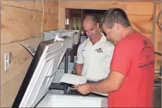  ?? / Doug Walker ?? Brian Moore (left) and Micah Studdard check out the inventory of Lyons Bridge Farm Beef in a cooler that is designated solely for shipment to Harvest Moon Cafe on Broad Street.