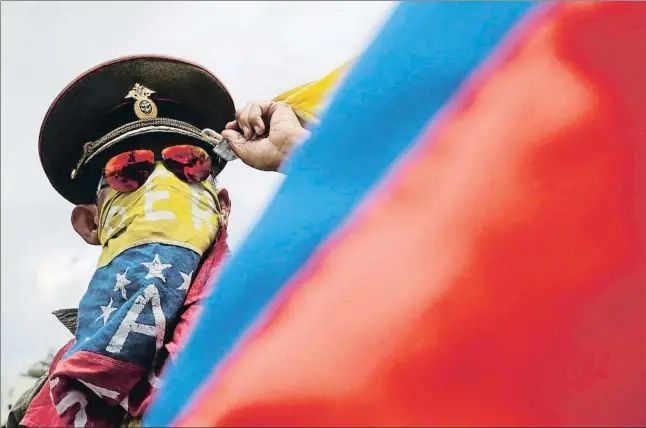  ?? WIL RIERA / AP ?? Un manifestan­te de la oposición con un sombrero militar ruso ondeando la bandera de Venezuela durante una protesta, ayer en Caracas