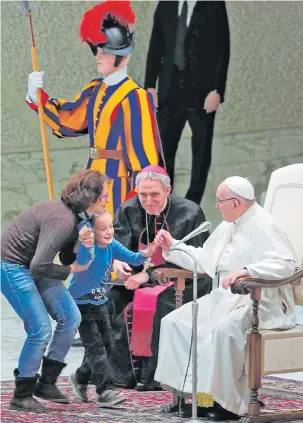  ??  ?? The mischievou­s boy is retrieved by his mother as the Pope holds his hand
