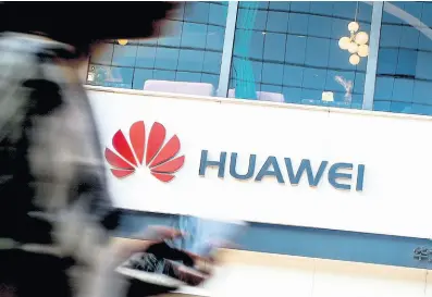  ?? AP ?? In this July 30, 2019 file photo, a woman walks by a Huawei retail store in Beijing. United States regulators are proposing to cut off funding for Chinese equipment in US networks, citing security threats.