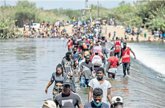  ??  ?? Haitians cross the Rio Grande River near a temporary migrant camp in Del Rio, Texas, at the weekend