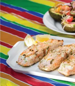  ??  ?? Salmon, brushed with dill mayonnaise, accompanie­d by grilled avocado halves bru