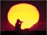  ?? AP Photo/Robert F. Bukaty ?? ■ A photograph­er composes a picture on the Camp Ellis jetty as the sun rises over the Atlantic Ocean on June 29, 2012, in Saco, Maine.