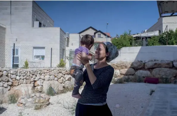  ??  ?? Enceinte de sa fille Shaked Ahava, ici dans ses bras, Michal Froman, qui vit à Goush, avait été poignardée par un jeune Palestinie­n. Elle a pardonné, dit-elle.