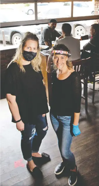  ?? GAVIN YOUNG ?? Garrison Pub general manger Shannon Roy, left and server Alexis Cooley welcomed customers on Monday. “We’re slowly doing better; we had a lineup out the door for the first time last Friday,” Roy said.