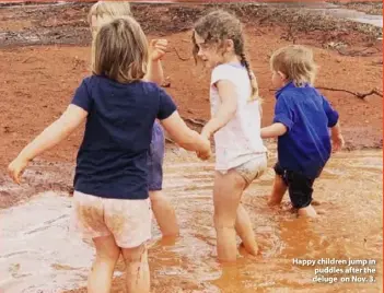  ??  ?? Happy children jump in puddles after the deluge on Nov. 3.