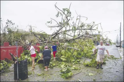  ?? AP PHOTO ?? A family helps clean the road after Hurricane Maria hit the eastern region of the island in Humacao, Puerto Rico. The strongest hurricane to hit Puerto Rico in more than 80 years destroyed hundreds of homes, knocked out power across the entire island...