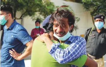  ?? Online ?? People comfort a relative of a victim near the site of a PIA aircraft crash in a Karachi residentia­l area in May. A total of 97 persons lost their lives in the crash, including 7 crewmember­s.