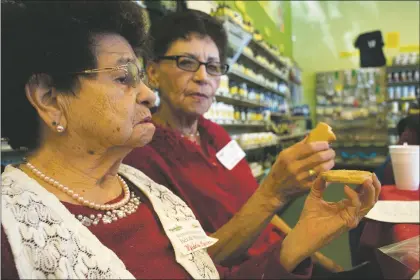  ?? Staci Matlock ?? From left: Biscochito judges Medalia Martinez (left foreground) and Ruby Montoya confer regarding an entry in the ninth annual contest held Dec. 13 at Taos Herb Co.