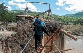  ?? GETTY IMAGES ?? People use a makeshift crossing over a river in Chipinge, Zimbabwe after a bridge was swept away by floodwater­s from Cyclone Idai.