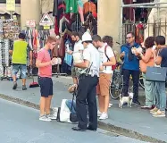  ??  ?? In alto un vigile mentre fa alzare alcuni ragazzi dal marciapied­e di via dei Neri A destra una famiglia sotto il Perseo in piazza della Signoria che non è inclusa nell’ordinanza anti bivacco