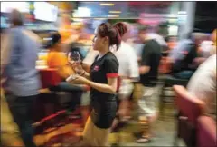  ?? SCOTT HOWES ?? A waitress takes an empty glass back to a service area at a Phnom Penh bar in 2014.