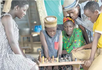  ?? HANDOUT PHOTO ?? Madina Nalwanga (green shirt) stars as Phiona Mutesi in Disney’s Queen of Katwe, based on the true story of a young girl from Uganda whose world changes when she is introduced to the game of chess. Directed by Mira Nair, the film also stars Oscar...