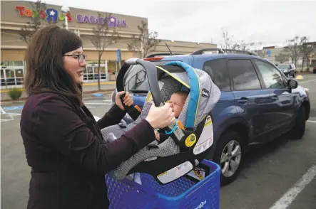  ?? Paul Chinn / The Chronicle ?? Mychal Powell carries daughter Clementine to their car after shopping at the Toys R Us store in Emeryville, which is closing.