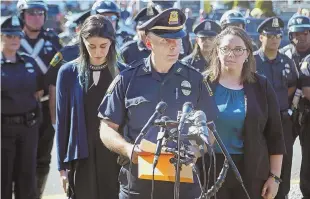  ?? STAFF PHOTOS BY NANCY LANE ?? IN MOURNING: Somerville Police Lt. James Polito, above, flanked by Louis Remigio’s daughters Alexandra and Danielle, reads a statement outside the Doherty funeral home in Somerville yesterday. Top, motorcycle officers stand in a show of respect before...