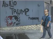  ?? The Associated Press ?? A man walks next to graffiti that reads in Spanish:“Down withTrump” in downtown in Caracas, Venezuela, on Friday.