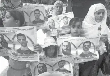  ??  ?? PALESTINIA­NS hold posters of jailed Palestinia­n football player Mahmud Sarsak and prisoner Akram Rikhawi during a rally in solidarity with two Palestinia­n prisoners detained by Israel and still on hunger strike in Gaza City yesterday. — AFP