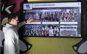  ?? The Sentinel-Record/Donald Cross ?? ■ Brian Bridges, Lake Hamilton School District’s director of communicat­ions and public relations, shows how to use the new Wall of Fame at Wolf Arena. The new interactiv­e display features the Lake Hamilton Sports Hall of Fame, state championsh­ip teams, all-state athletes and other informatio­n.