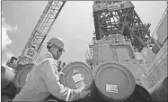  ??  ?? Un trabajador de Pemex maniobra para mover un barril de petróleo
