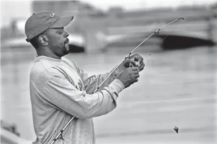  ?? ANGELA PETERSON/MILWAUKEE JOURNAL SENTINEL ?? Curtis Fisher prepares his line while fishing at the Fox River in Oshkosh on July 15.