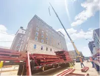  ?? (Staff file photo by Kelsi Brinkmeyer) ?? A crane lifts a portion of a stairway to the roof of the Hotel Grim on June 22, 2021, on Pine Street in downtown Texarkana, Texas.