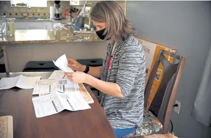  ?? Jessica Hill, The Associated Press ?? Melissa Wilhelm Szymanski opens up some of her medical bills at home in Glastonbur­y, Conn., on Saturday, Sept. 19. Szymanski spent five hours in a Hartford, Conn., emergency room in late March and wound up with bills totaling about $ 3,200.