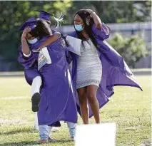  ?? Karen Warren / Staff photograph­er ?? Graduating seniors hug as they get seated during the virtual graduation ceremony at Wheatley High School.