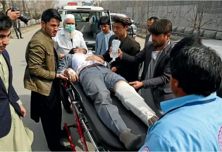  ?? AP ?? An injured man is carried to an ambulance after gunmen attacked a remembranc­e ceremony for a Shiite Muslim leader in Kabul, killing at last 32 people and wounding dozens.