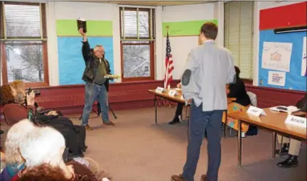  ?? BILL KEMBLE PHOTO ?? Firearms instructor James Meineker holds up a book of New York state laws to object to any new regulation of firearms during Tuesday’s Town Hall event at Kingston Library.