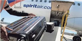  ?? SAM HODGSON/BLOOMBERG ?? A ground crew member loads baggage onto a Spirit Airlines plane in San Diego. Spirit charges more for bags during peak travel times.
