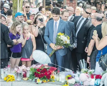  ?? PETER J THOMPSON / NATIONAL POST ?? Prime Minister Justin Trudeau places flowers at a makeshift memorial on Toronto’s Danforth Avenue on Monday for victims of the July 22 mass shooting. “Obviously there’s a lot of strong emotions going on,” he said.