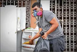  ?? THOMAS CORDY / THE PALM BEACH POST ?? A resident empties a refrigerat­or of rancid food Sept. 30 in Santa Isabel on the southern coast of Puerto Rico. The U.S. House is expected to vote this week on an emergency spending package including billions more in relief for Puerto Rico, Texas and...