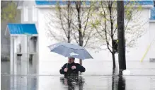  ??  ?? A man ventures through waist-high water flooding a residentia­l street in Gatineau, Que., on Saturday.