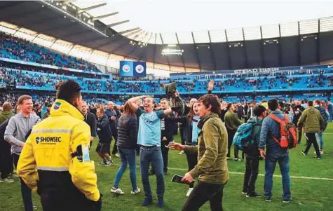  ?? AFP ?? Fans invade the pitch at the end of the Premier League match between Manchester City and Swansea City at the Etihad Stadium on Sunday. Manchester City won the match 5-0.