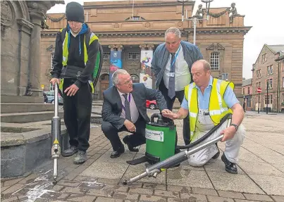  ?? Picture: Steven Brown. ?? John Spark, right, senior project officer, demonstrat­es to councillor Peter Barrett and Chris Ahern, convener, community justice committee, the new chewing gum removal machines, one of which is being operated by Christian Robson, 23, left, community...
