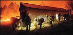  ?? NOAH BERGER / AP ?? In this Sept. 9 file photo, a hand crew clears vegetation from around a barn as the Bear Fire burns through the Berry Creek area of Butte County.