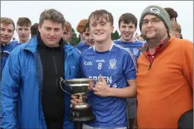  ??  ?? David Hennebry, Ballyhogue captain, accepts the trophy from David Tobin (Coiste na nOg Secretary) and Dean Goodison, representi­ng People Newspapers.