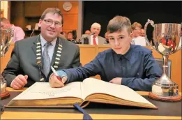  ??  ?? Conor McDonagh who was 1st Flute, Drums and Duet in the All Ireland Fleadh signing the Distinguis­hed Visitor’s Book